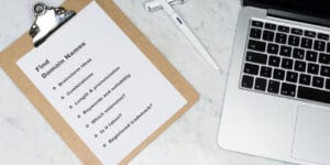 Checklist written on a clipboard showing list items to consider when planning a website, next to a laptop computer