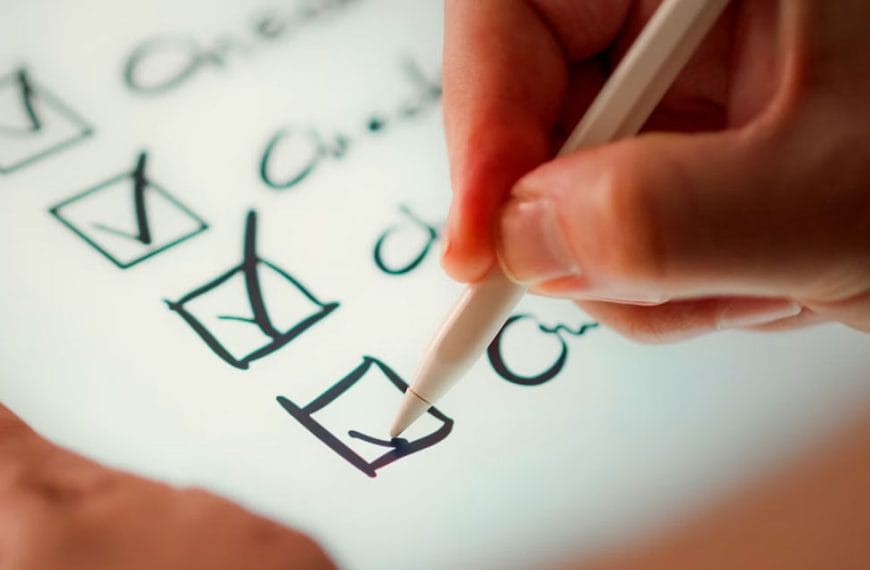 Close up of a hand holding a pen, ticking off items on a checklist.