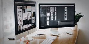 Two computer monitors open, one showing a website plan and the other showing some layout options.